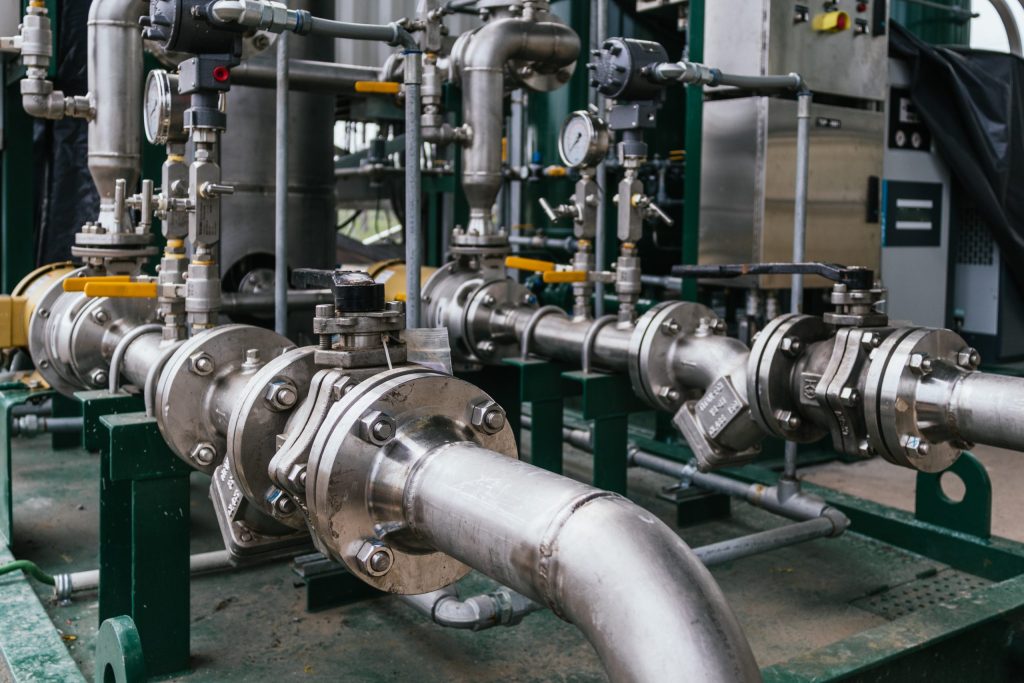 Vue rapprochée d'une tuyauterie industrielle en inox sur skid : brides boulonnées, vannes manuelles et instrumentation de mesure, source de vibrations en fonctionnement